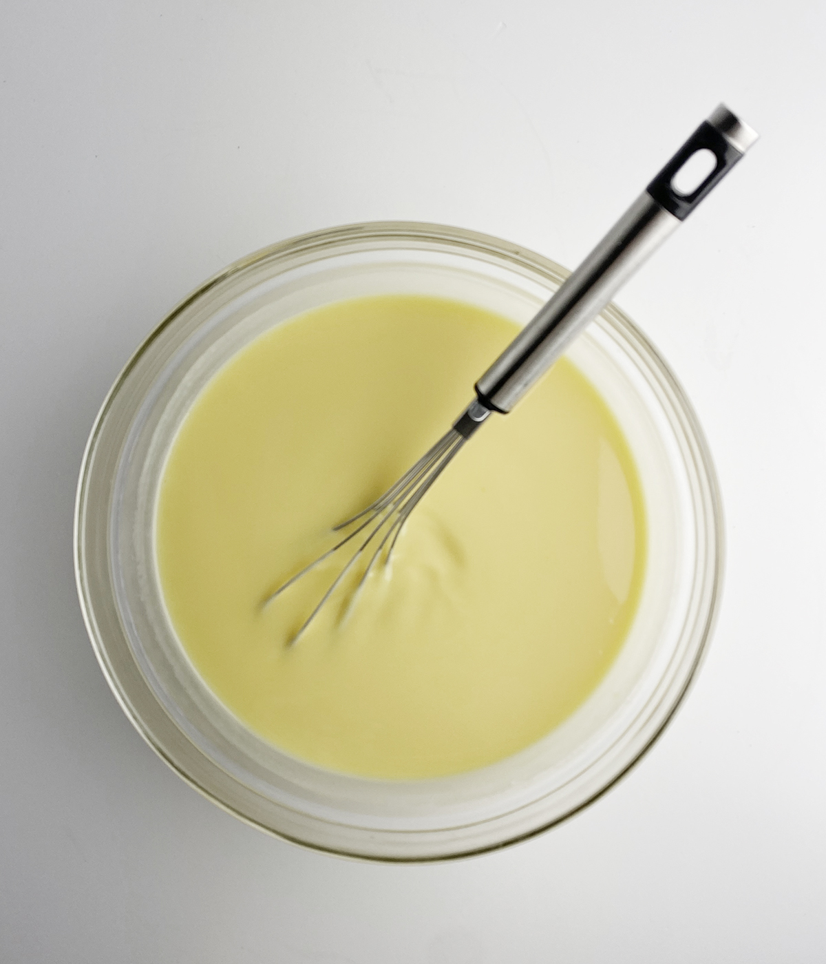 Vanilla pudding in a bowl with a whisk.