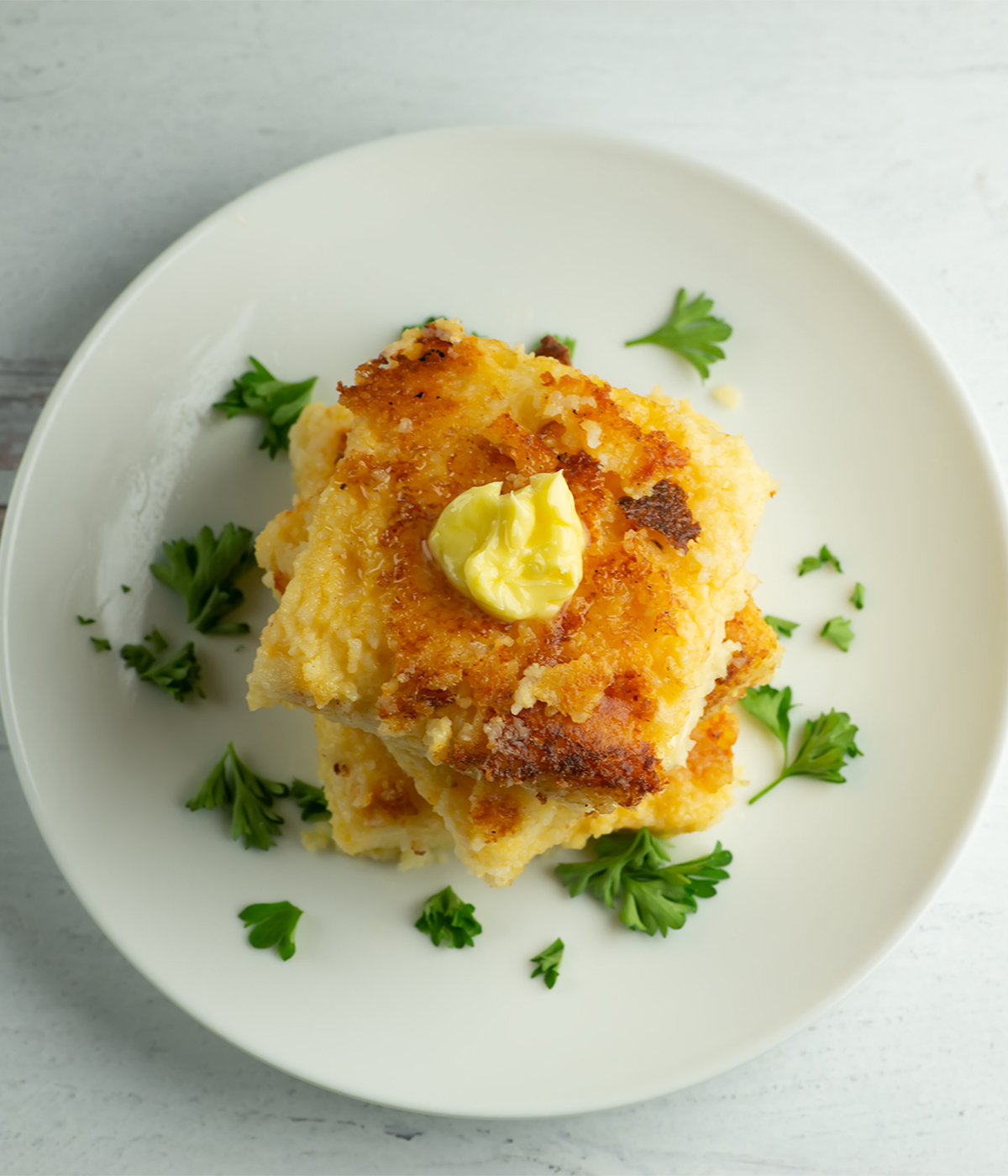 Cheesy grit cakes with butter on a plate.