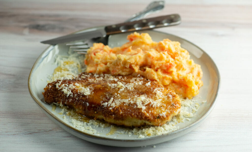 fried parmesan chicken on plate with fork and knife