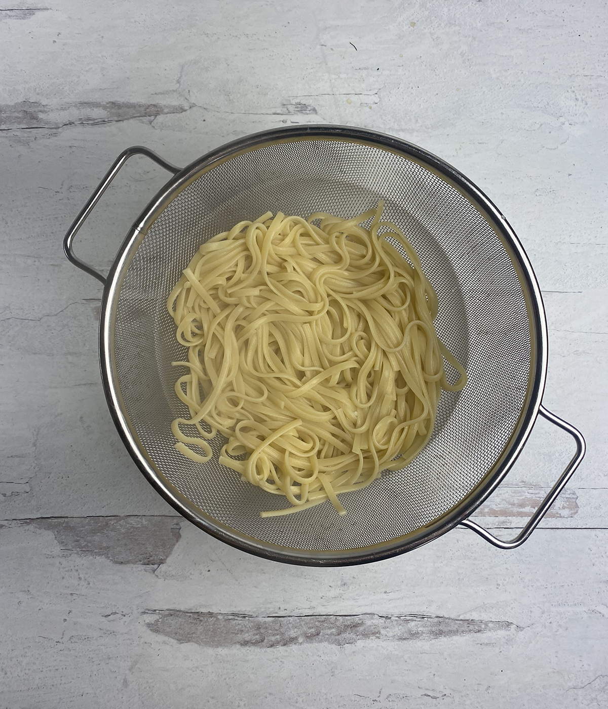 Cooked pasta in a strainer draining.