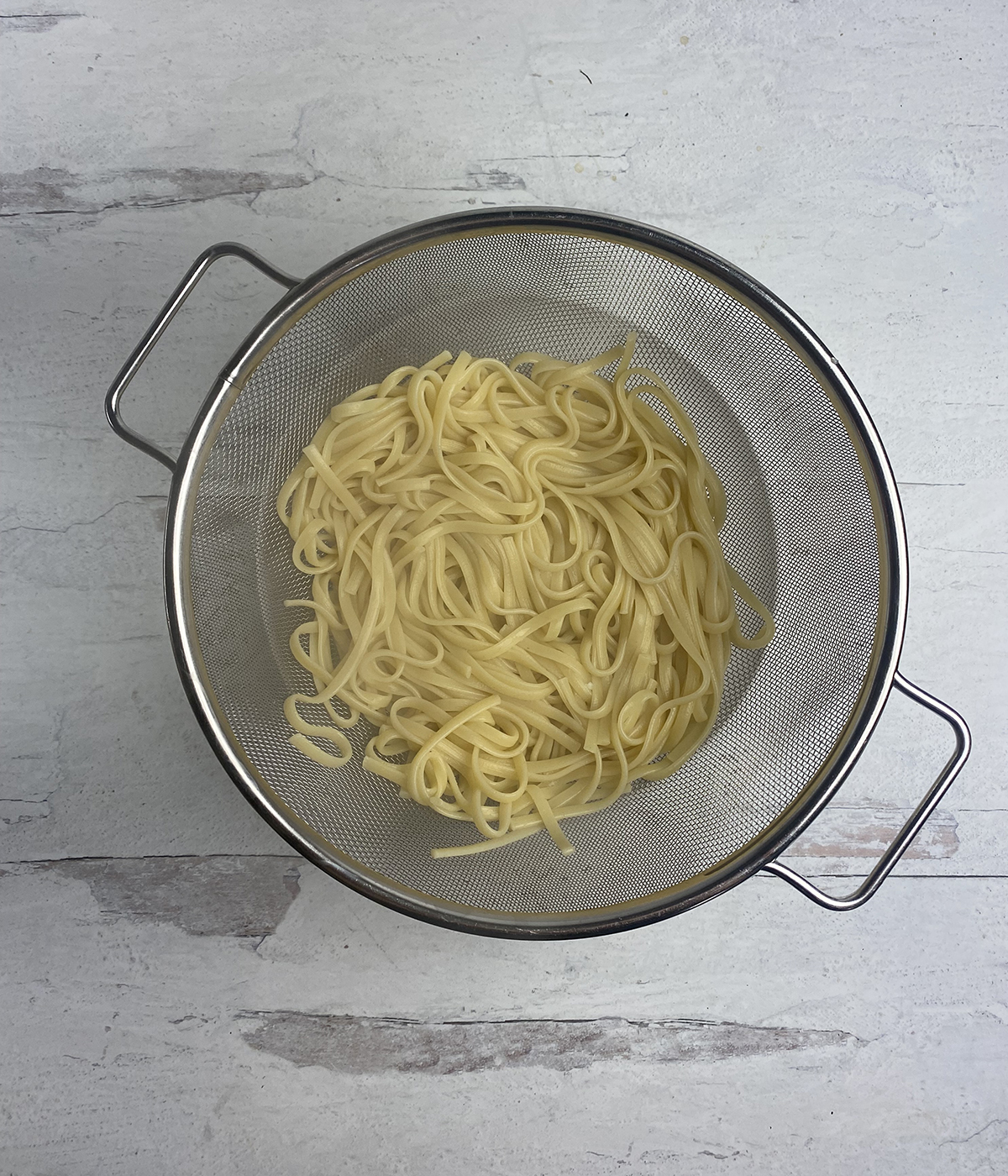Cooked pasta in a strainer draining.
