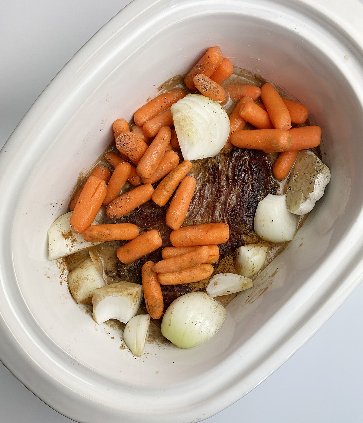 Coca cola pot roast ingredients in a slow cooker ready to be cooked.
