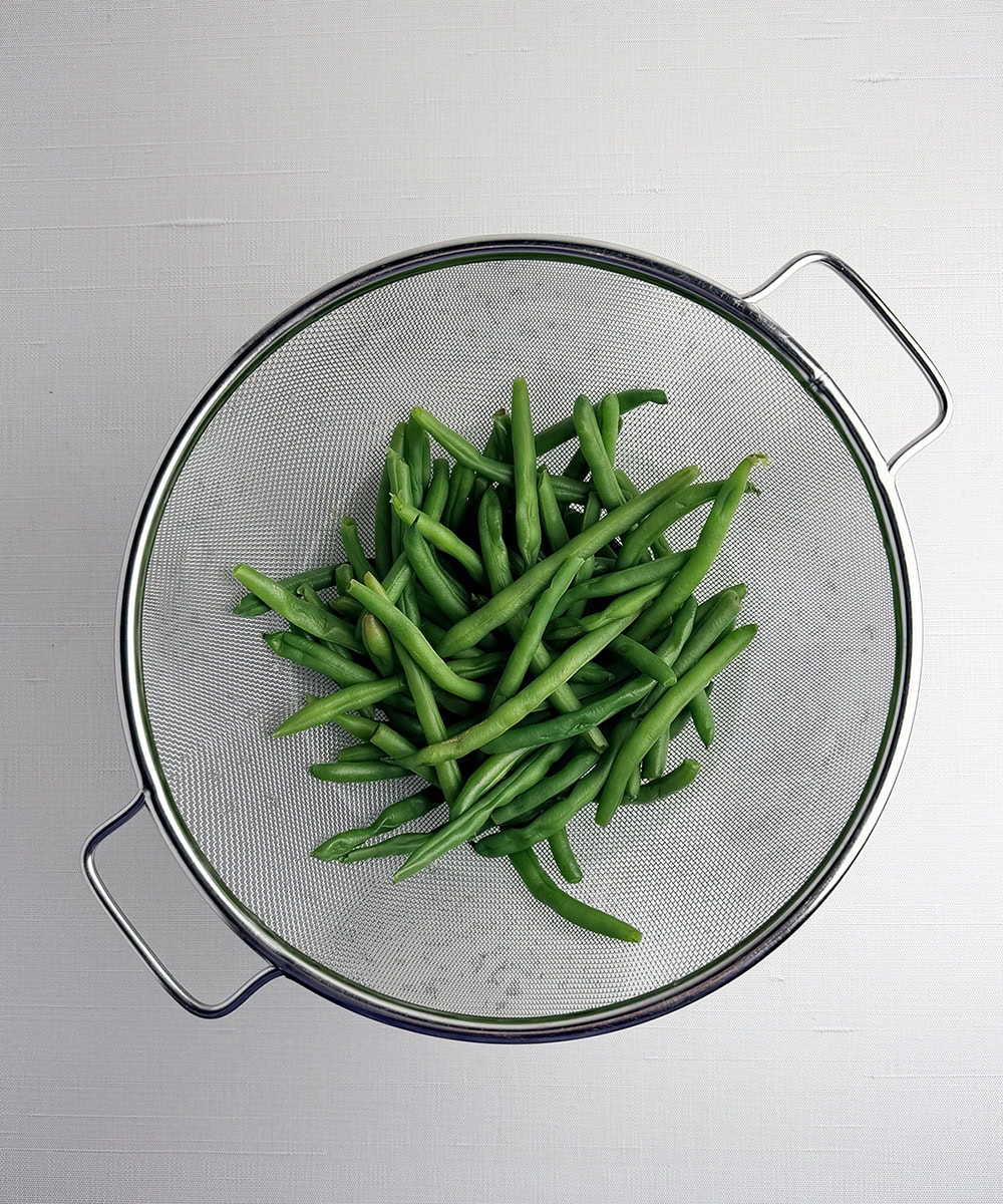 Green beans in a strainer.