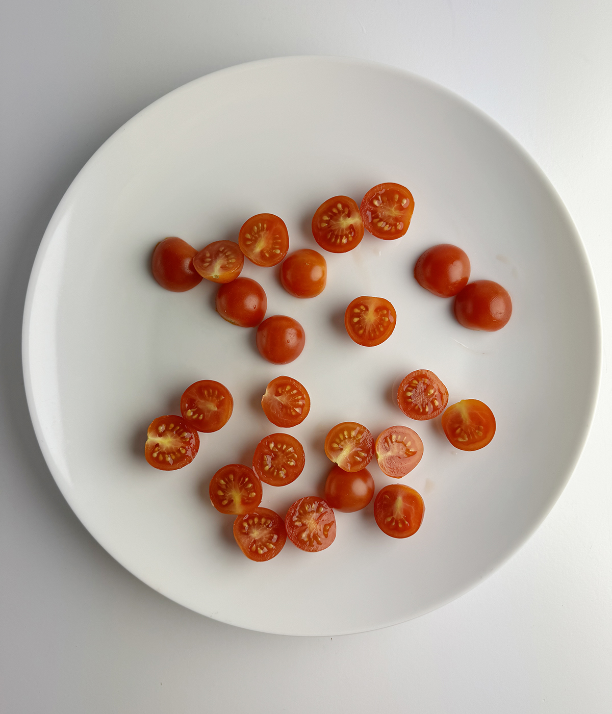 Halved cherry tomatoes on a plate.