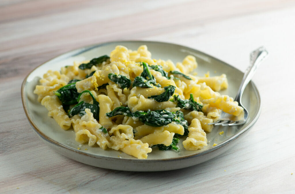 Pasta with lemon ricotta spinach sauce on a plate with a fork.