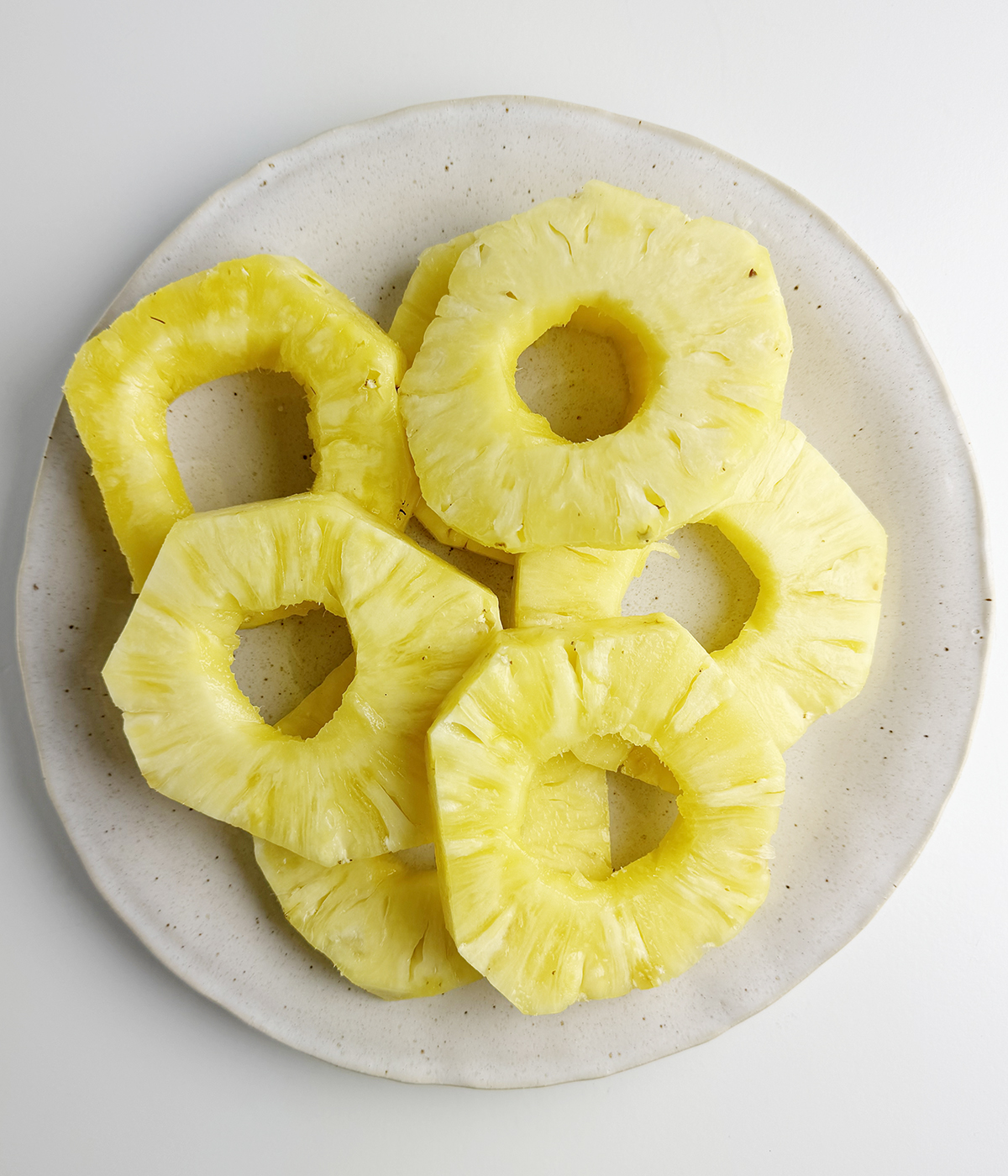 Sliced pineapple rounds on a plate.