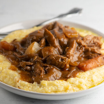Slow cooker coca cola pot roast on a plate with grits.