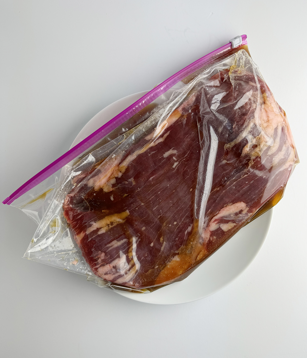 Steak marinating in a zippered plastic bag.