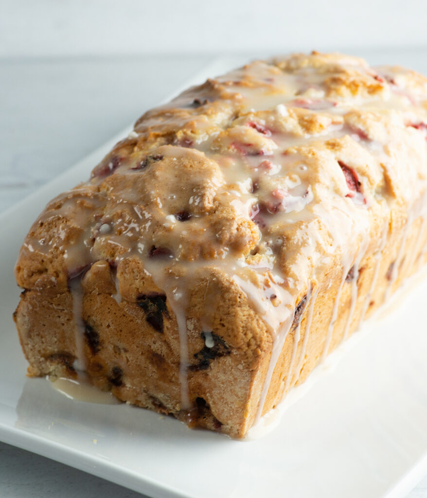 A loaf of glazed strawberry bread on a plate.