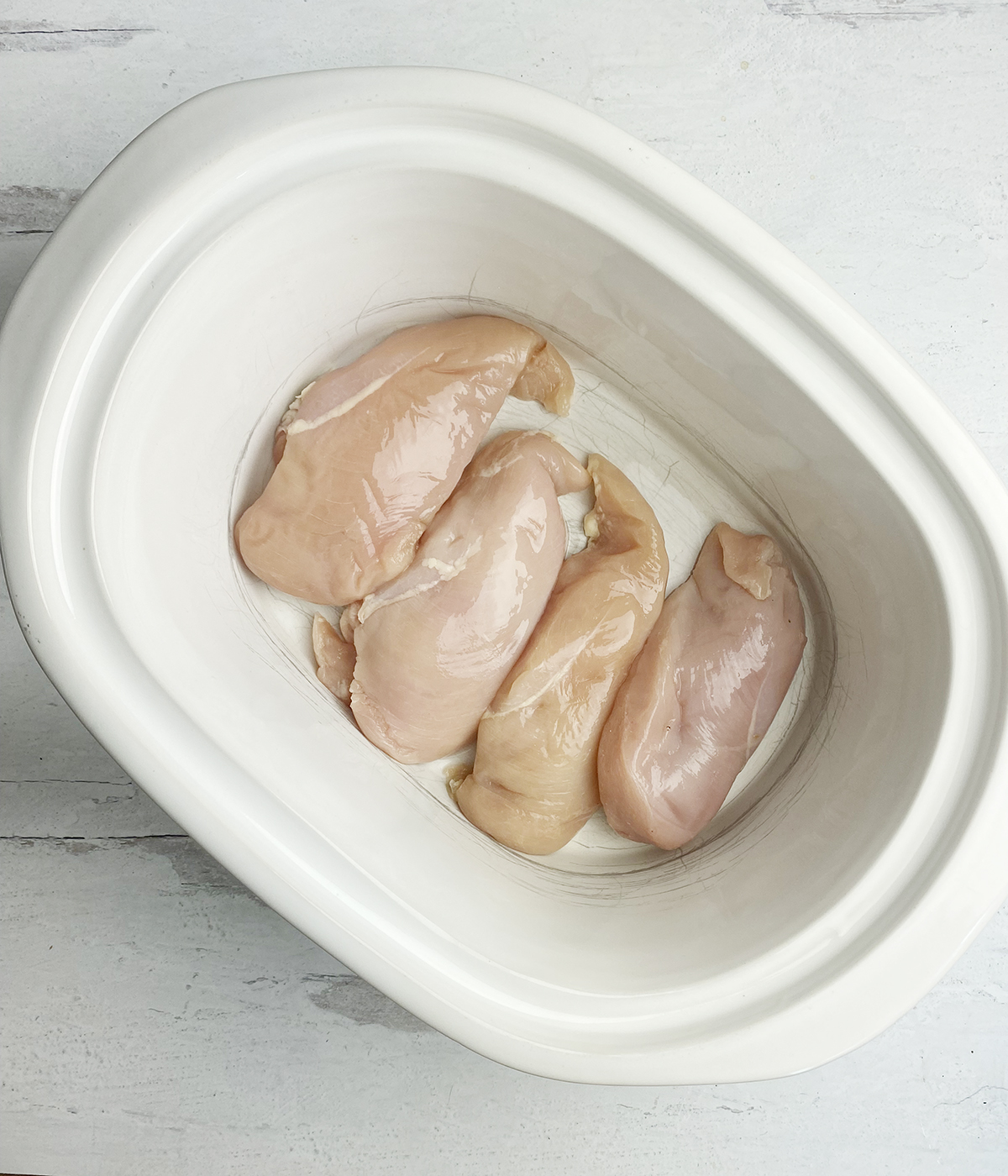 Boneless chicken breasts in a slow cooker.