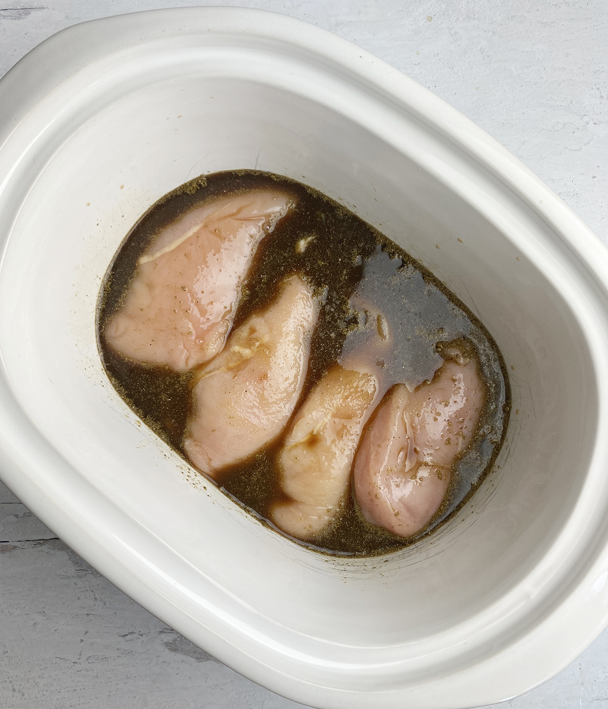 Chicken with brown sugar sauce in a slow cooker ready to be cooked.