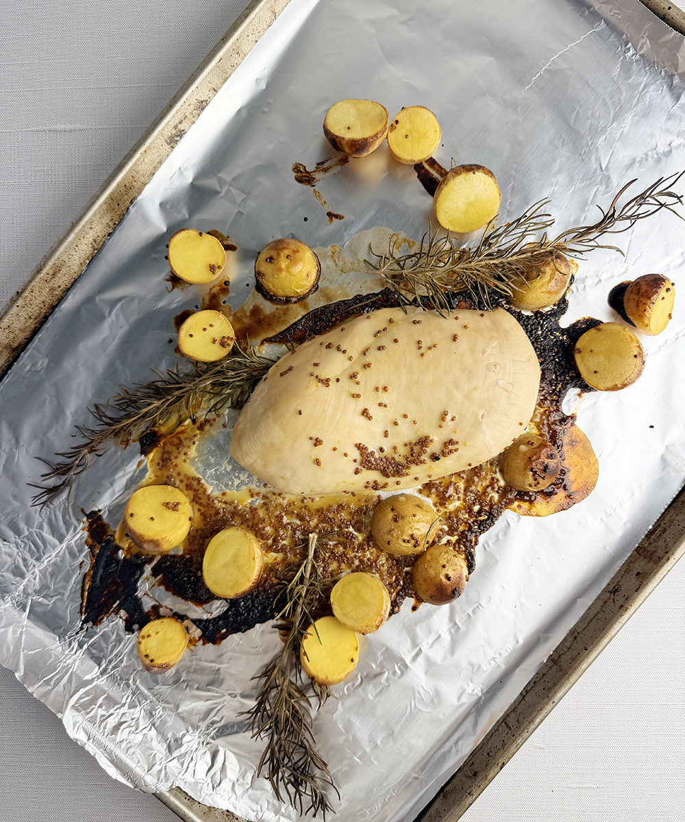 Roasted chicken and potatoes on a baking pan.