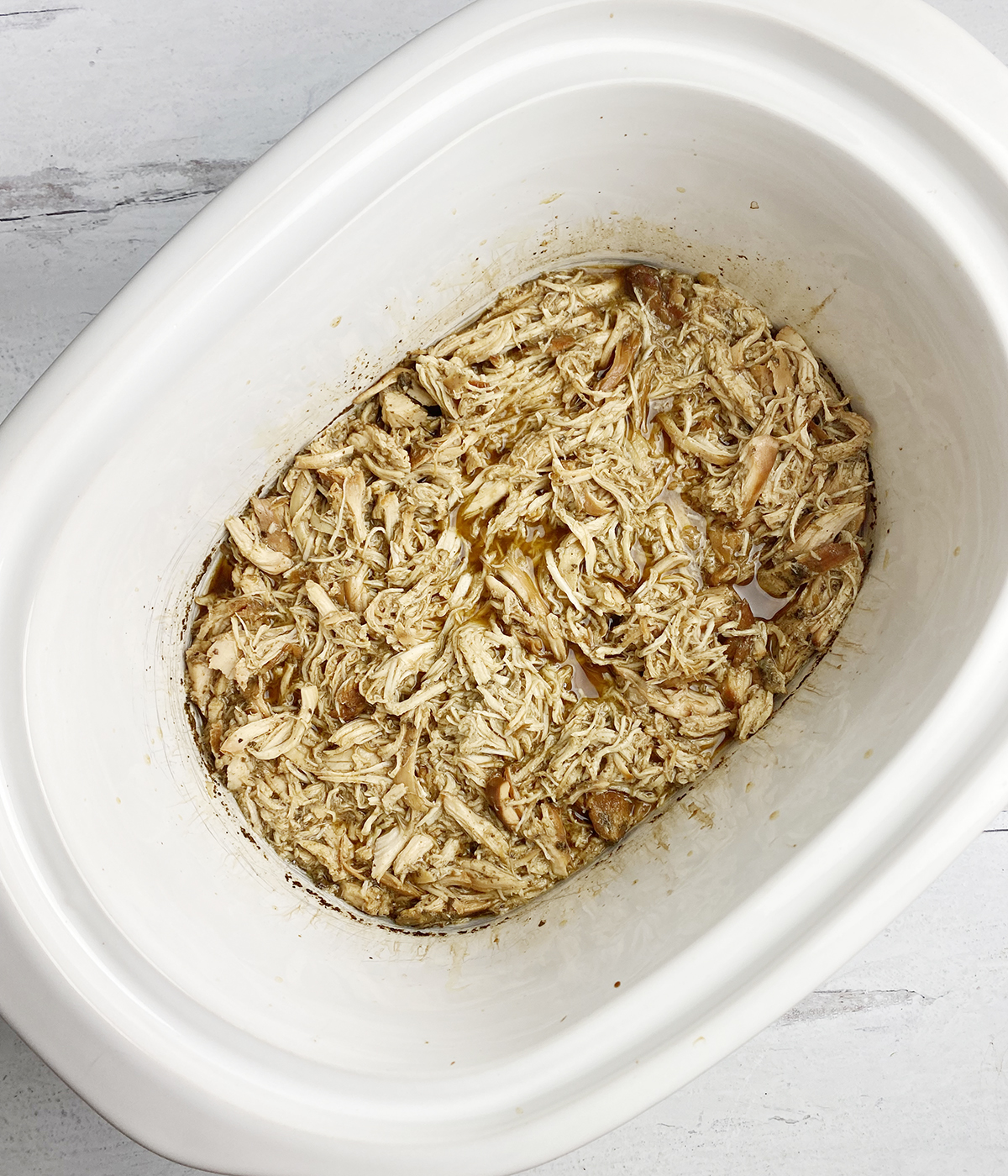 Shredded brown sugar chicken in a slow cooker.