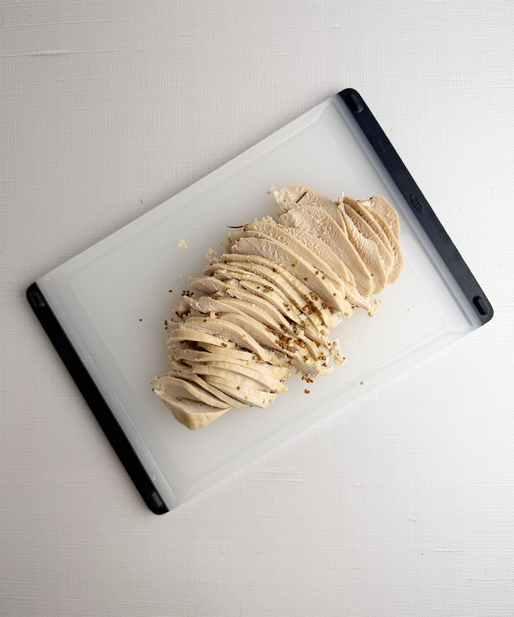 Thinly sliced chicken on a cutting board.