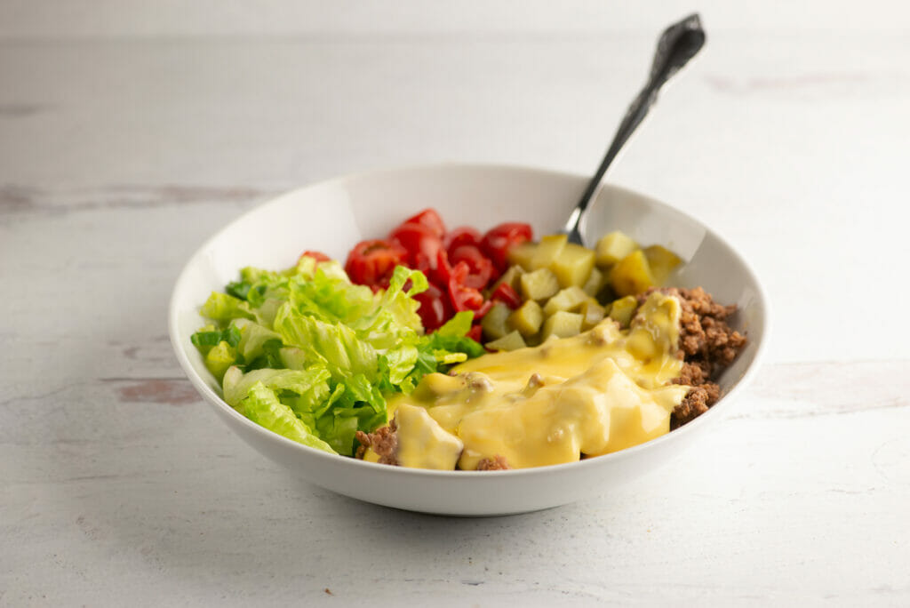 Cheeseburger bowl with a fork on a wooden counter.