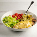 Cheeseburger bowl with a fork on a wooden counter.