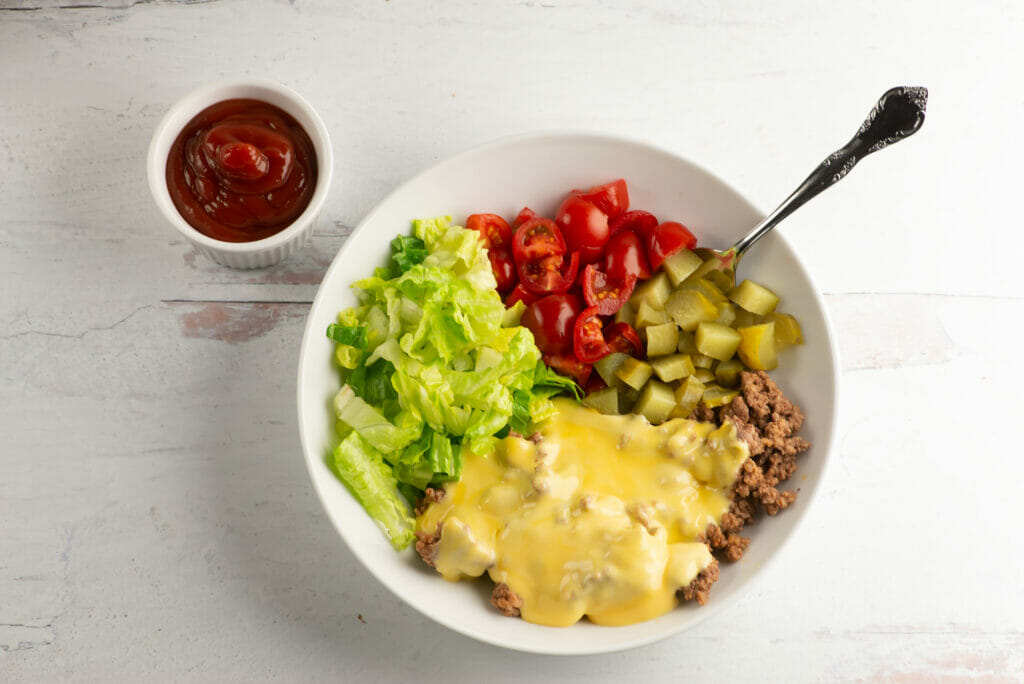 Cheeseburger bowl with fork on a wooden counter.