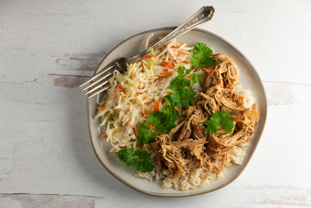 Plate of slow cooker brown sugar pulled chicken with coleslaw.