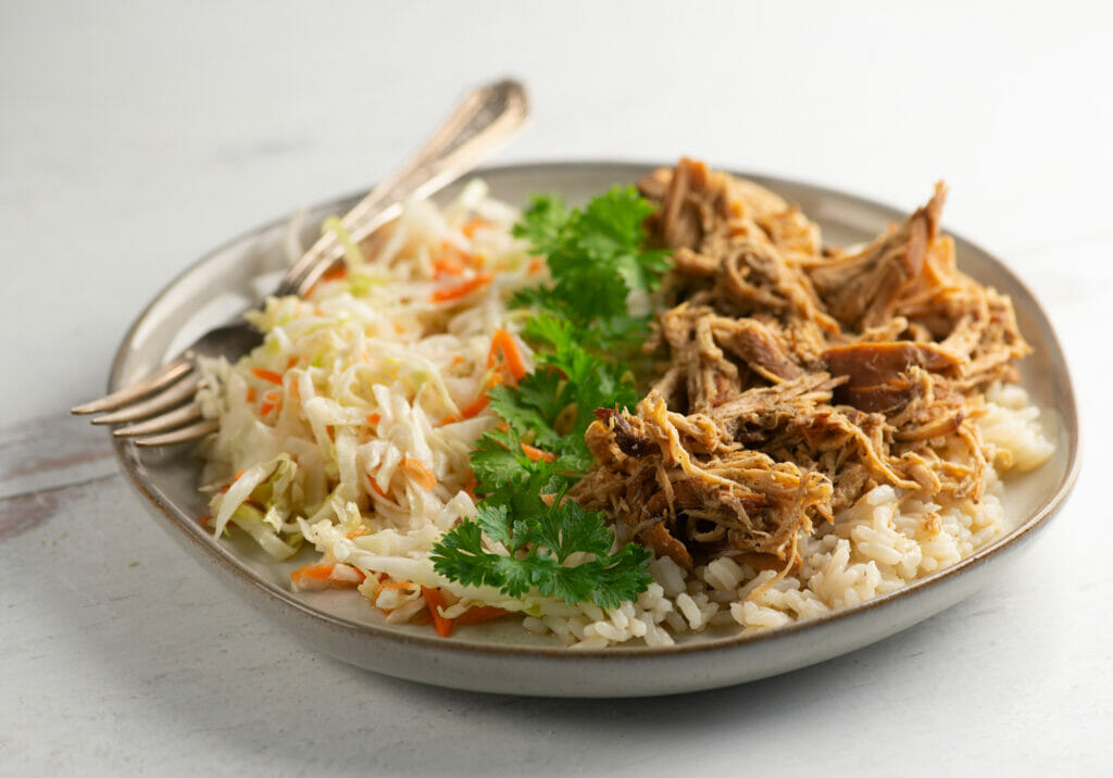 Slow cooker brown sugar pulled chicken on a plate with coleslaw.