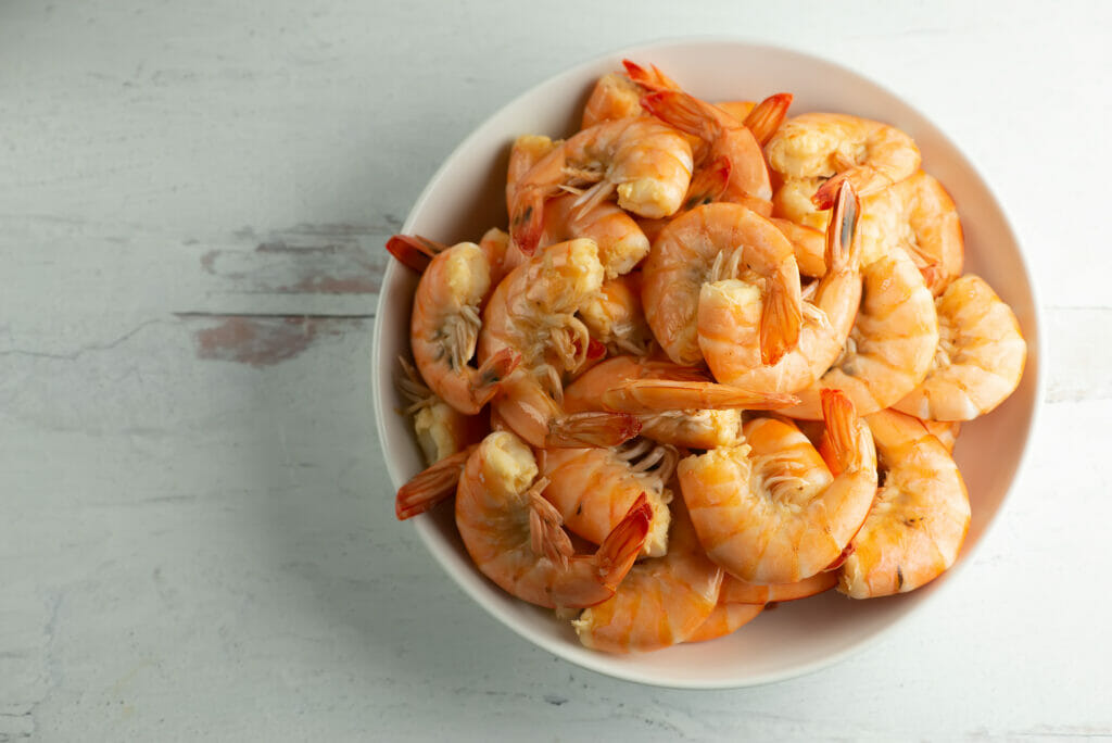 Bowl of shrimp cooked in beer sitting on a wooden counter.