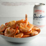 Shrimp cooked in beer in a bowl with a can of beer in the background.