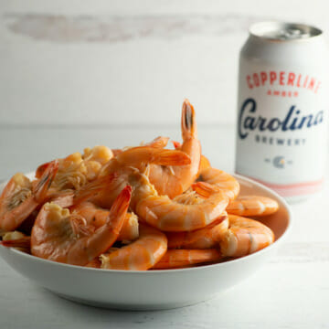 Shrimp cooked in beer in a bowl with a can of beer in the background.