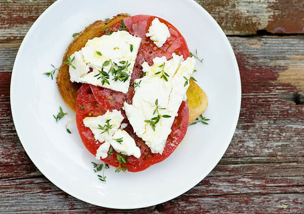 Open Faced tomato sandwich with feta cheese on a plate.