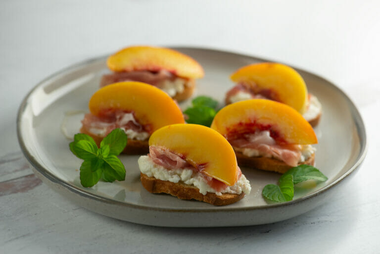 Plate of peach crostini with mint.