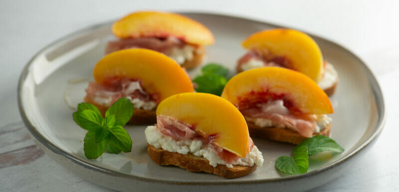 plate of peach crostini with mint