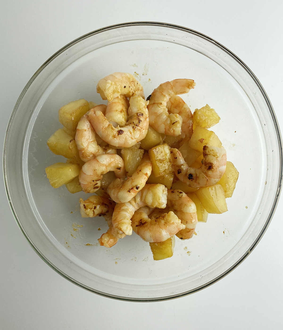 Pineapple and shrimp marinating in a bowl.