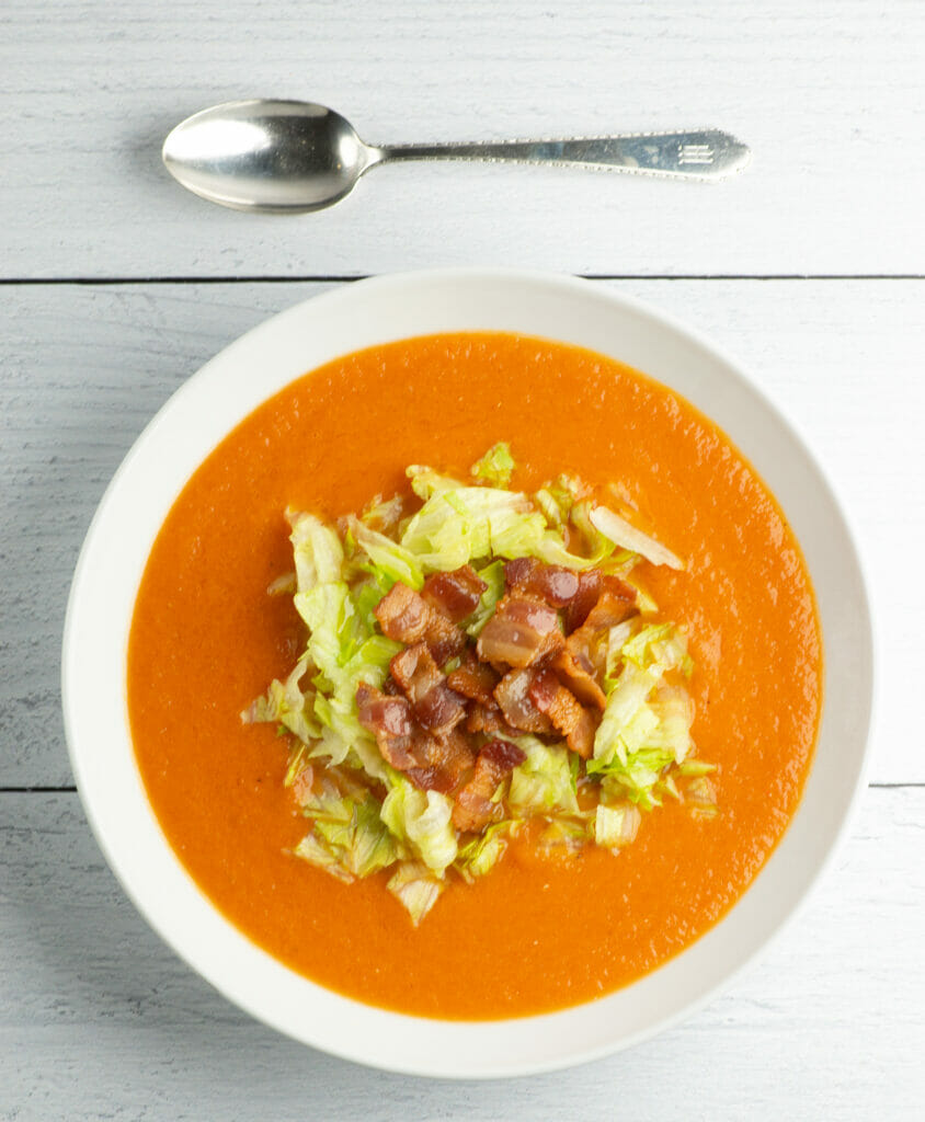 Bacon lettuce and tomato soup in a bowl on a wooden counter.