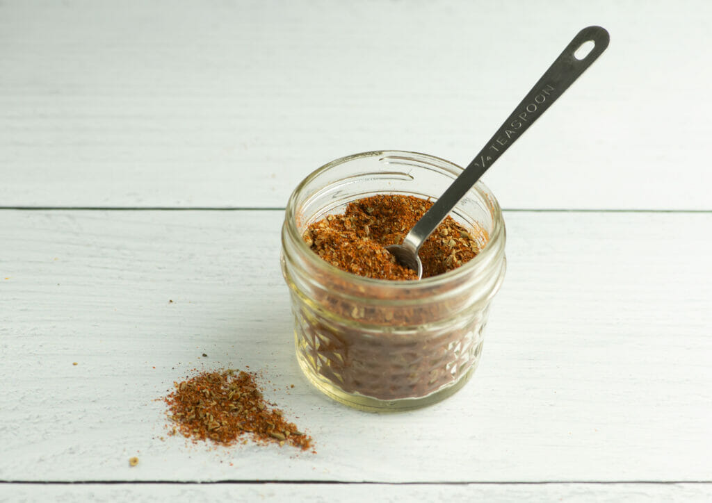 Easy homemade taco seasoning in a jar with a measuring spoon.