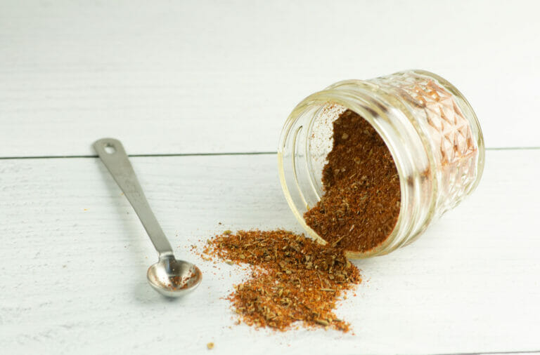 Homemade taco seasoning with a jar and a measuring spoon.