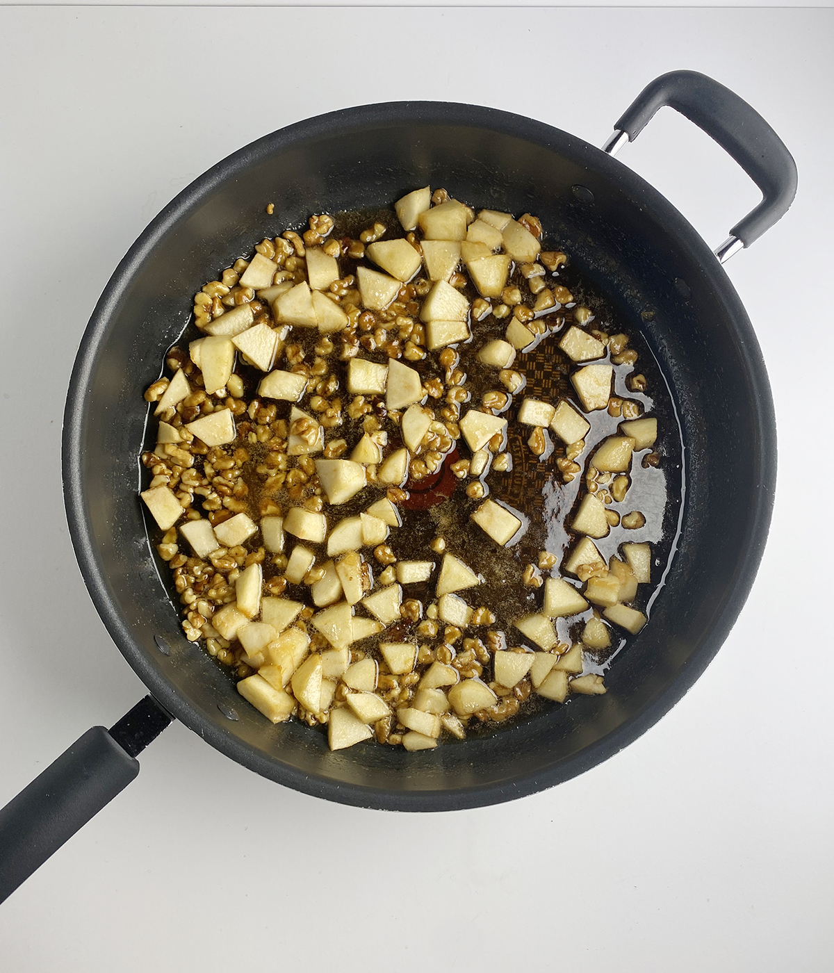 Apples with walnuts and maple syrup and brown sugar cooking in skillet.