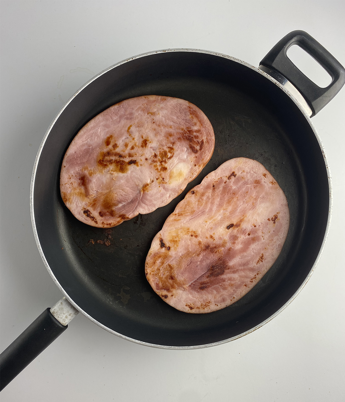 Browned ham steaks in a skillet.