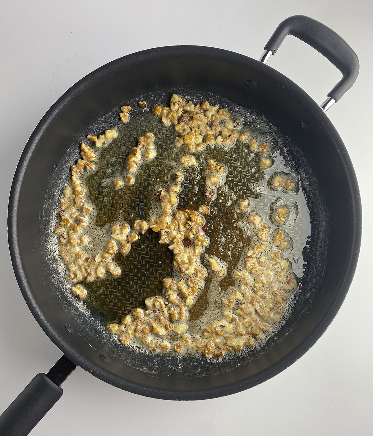 Walnut pieces browning in butter in skillet.