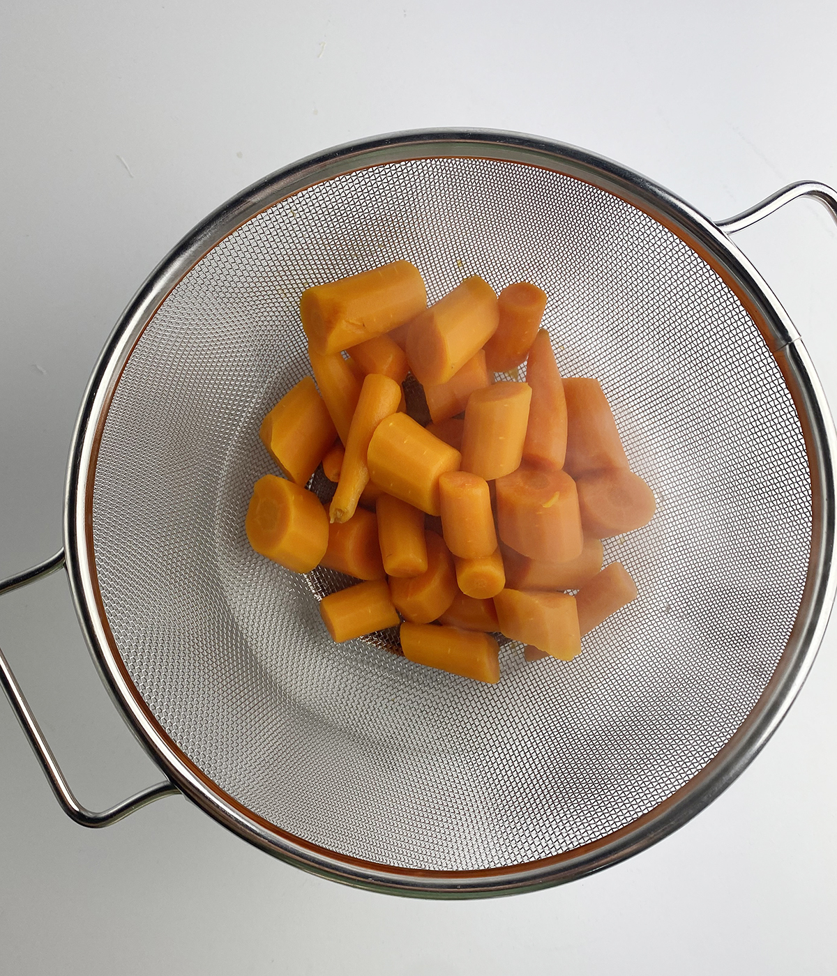 Cooked carrots in a strainer.