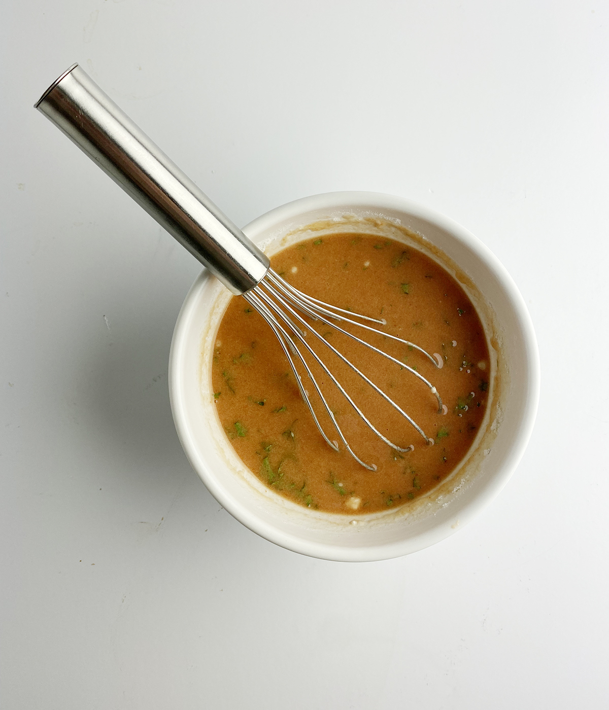 Sauce for slow cooker turkey pot roast in a bowl with a whisk.