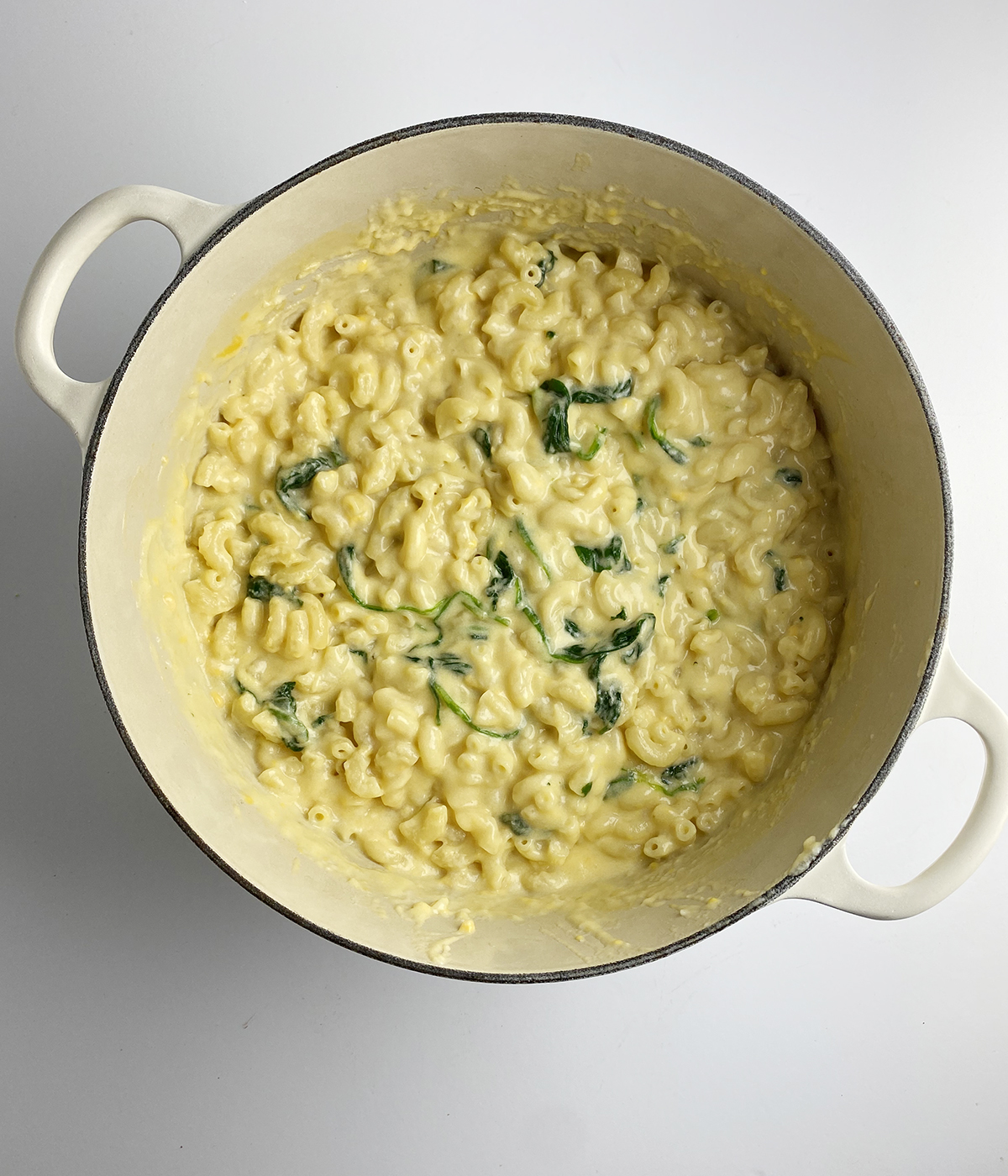 Macaroni and cheese with spinach in a Dutch oven.