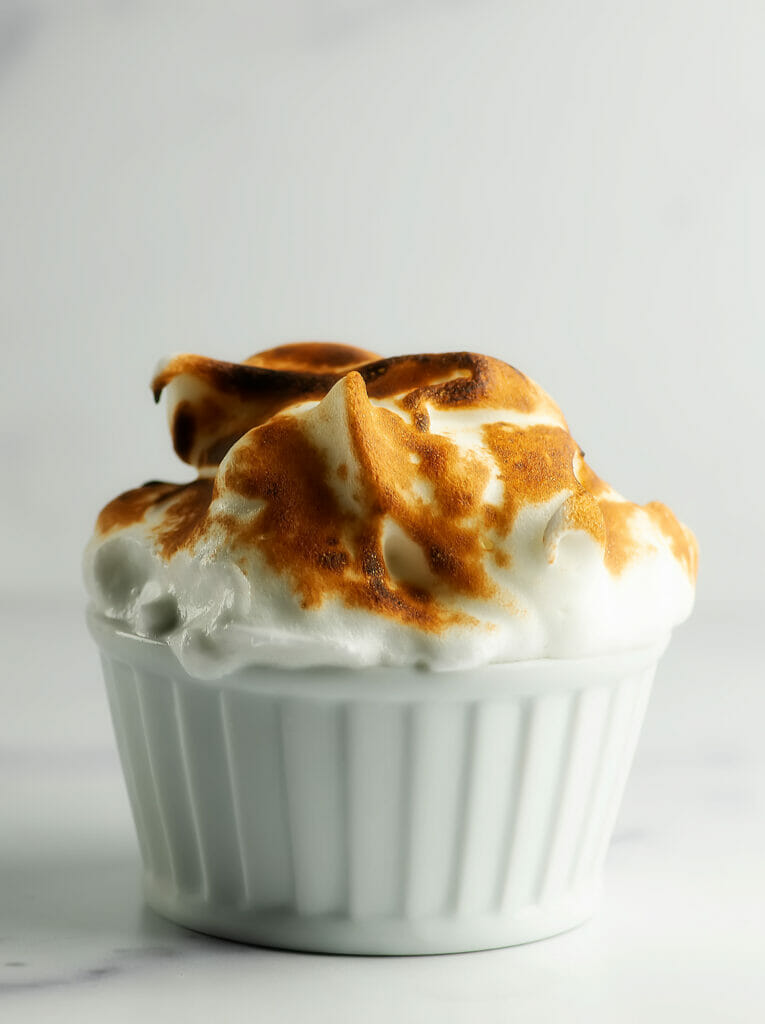 Mini baked alaska dessert in a white ramekin.