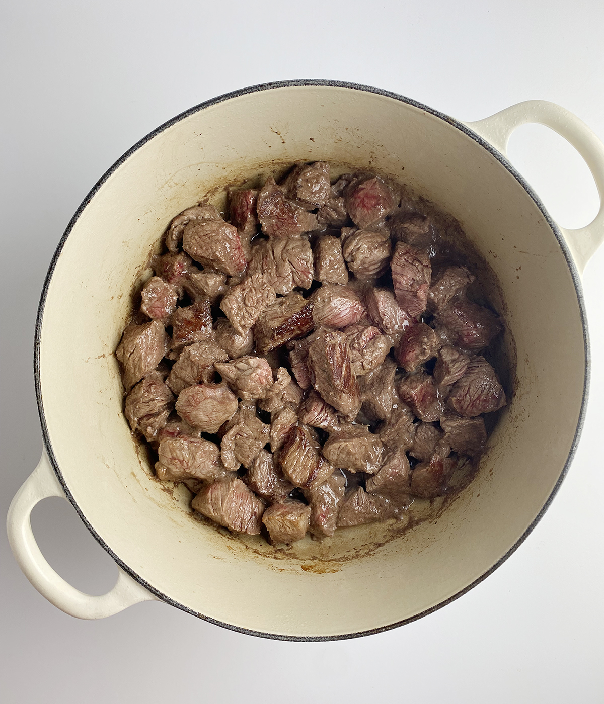 Seared beef chunks in a pot.