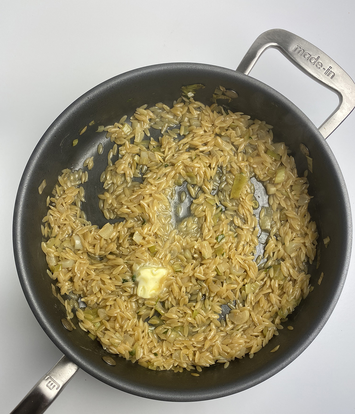 Lemon orzo in a skillet with some butter.