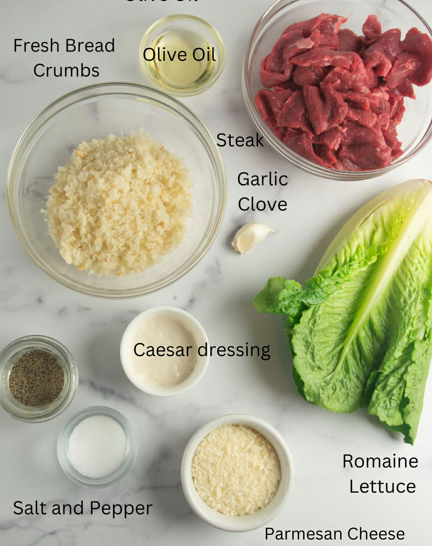 Steak Caesar Salad ingredients on a marble counter.