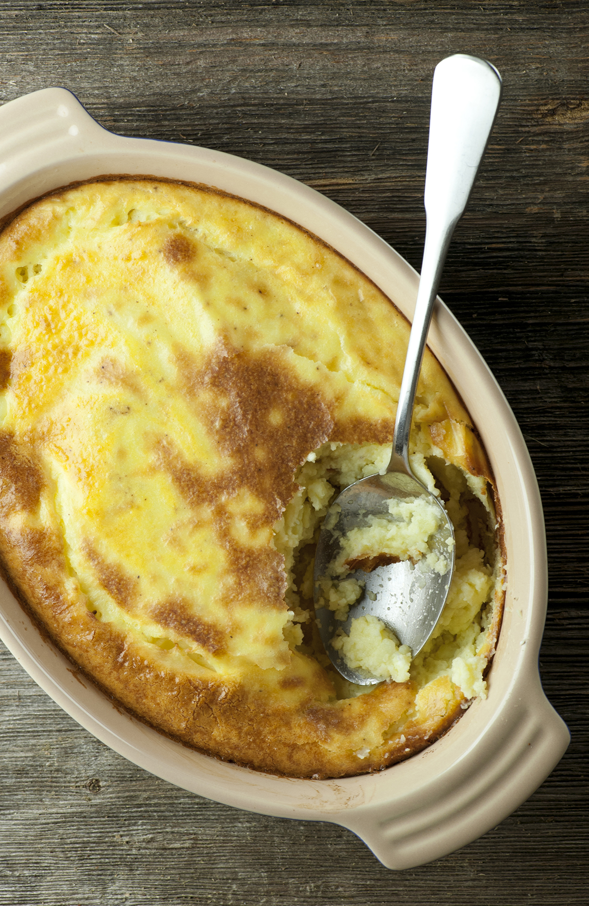 Baked mashed potatoes in a casserole with a spoon.