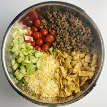 All ingredients for corn chip taco salad ready for mixing in mixing bowl.