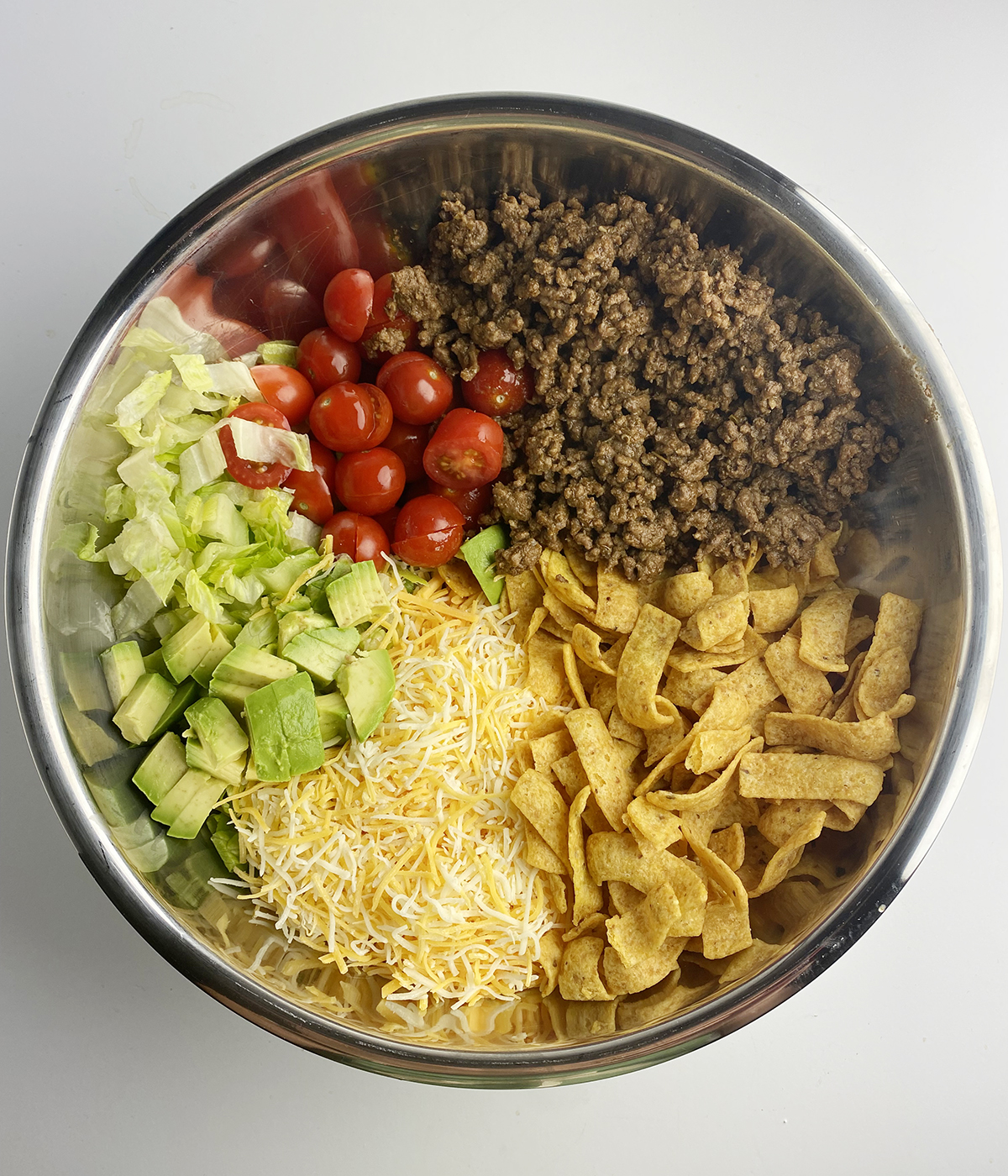 All ingredients for corn chip taco salad ready for mixing in mixing bowl.