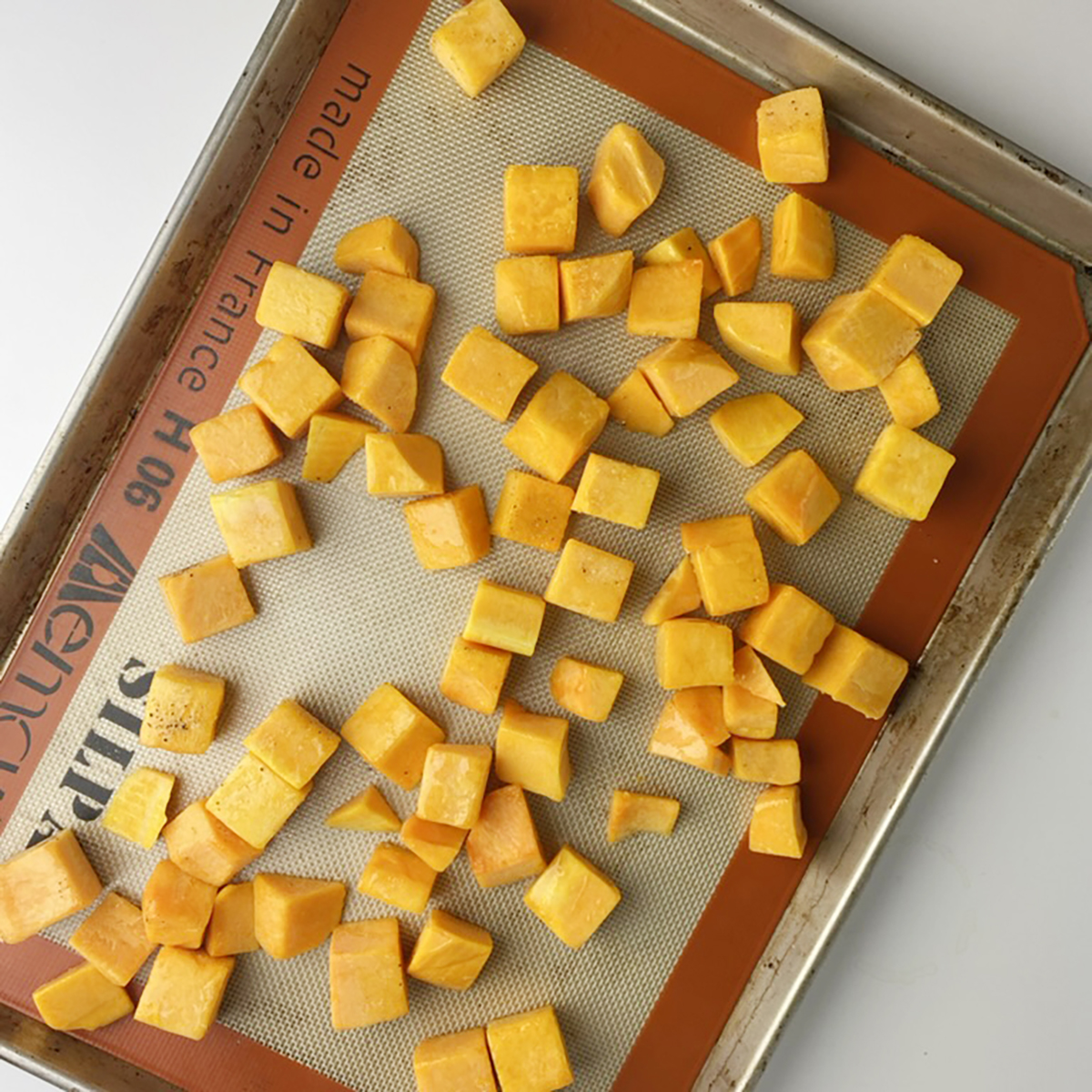 Butternut cubes on a baking tray.