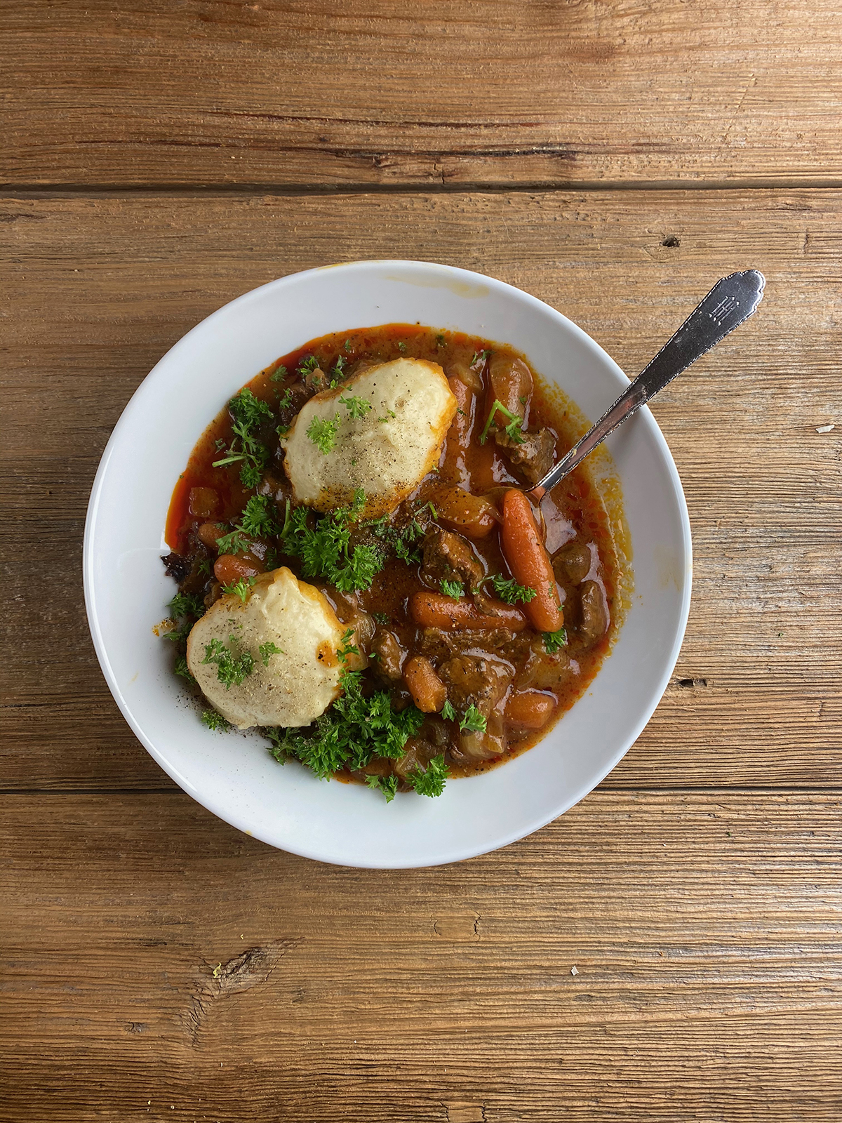 Bowl of beef dumpling stew on a wooden counter.