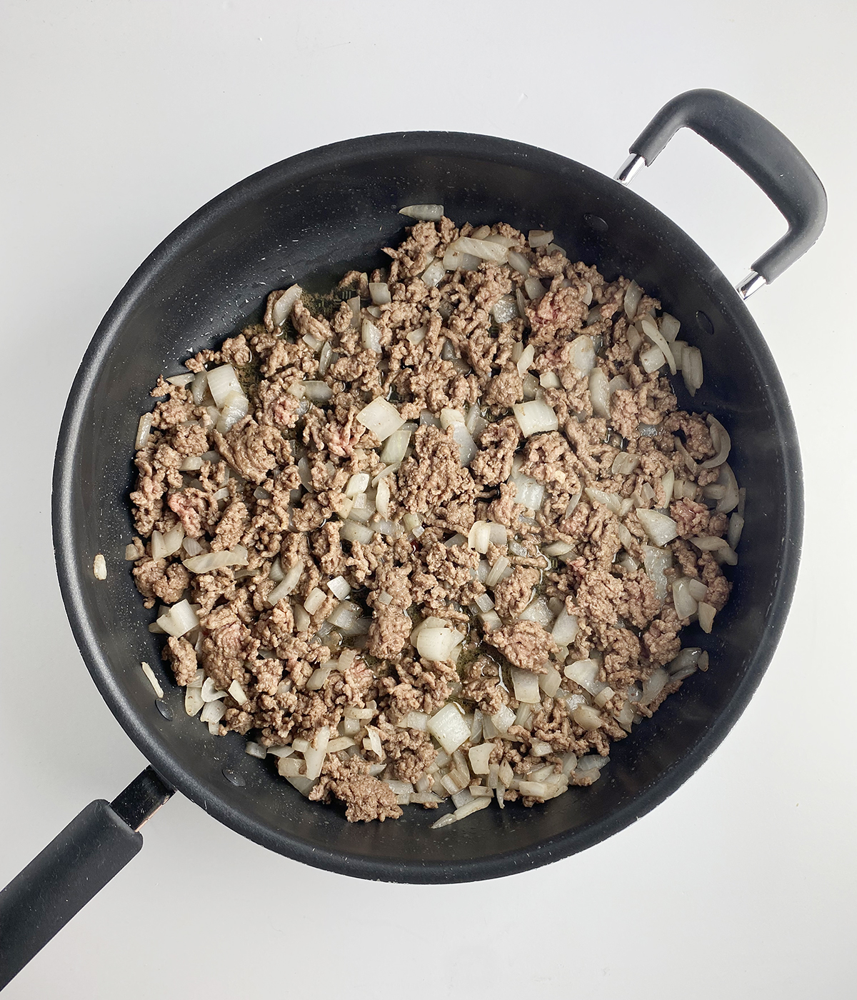 Cooked ground beef and onion in a skillet.