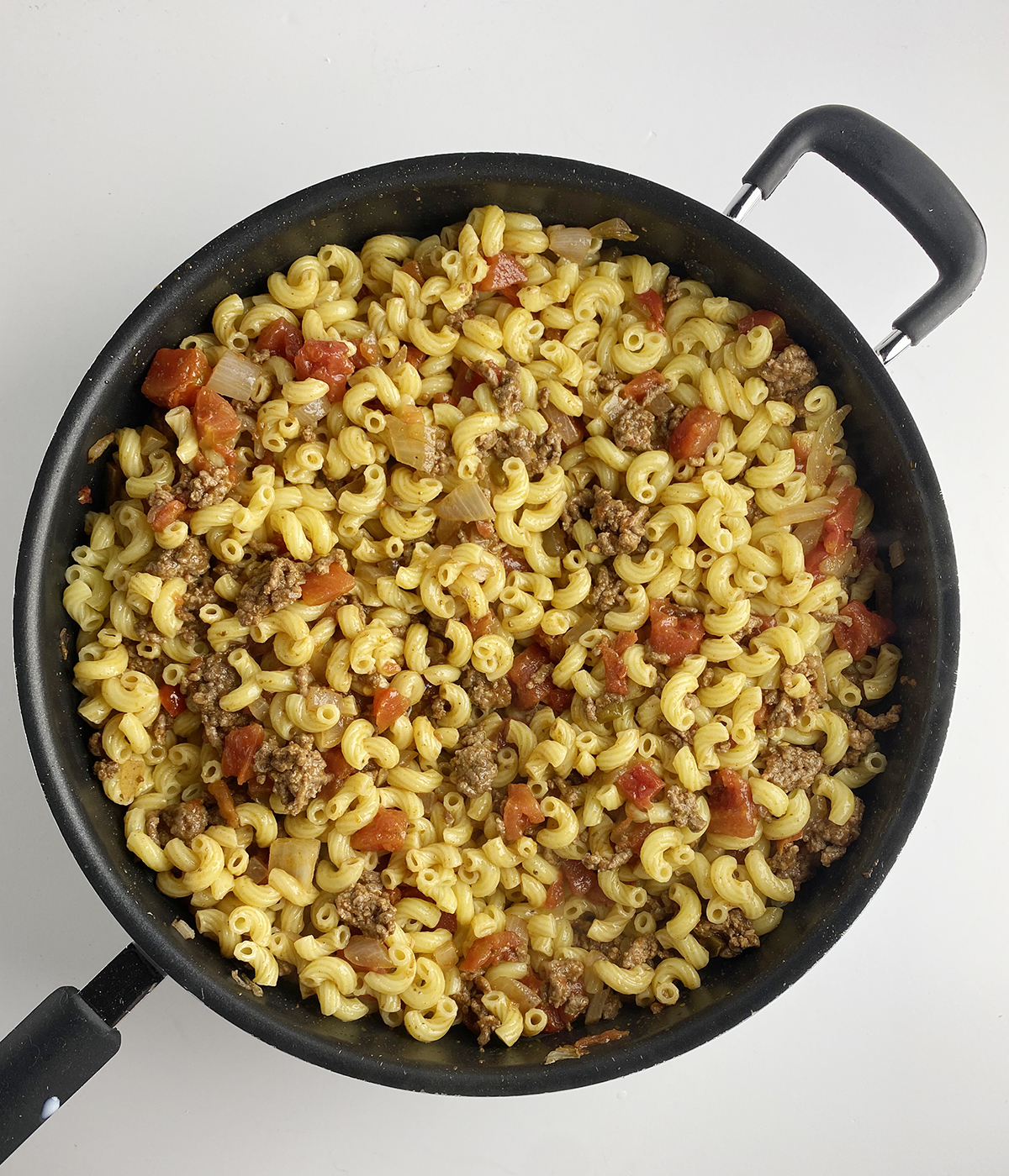 Elbow macaroni and taco meat in a skillet.
